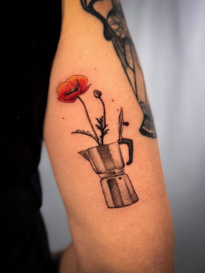 Tatuaggio surreale fine line di una moka stilizzata da cui nasce un fiore rosso aranciato, con dettagli puntinati e ombreggiature soft sul braccio